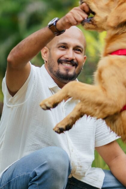 Smiling man reaching toward golden retriever dog