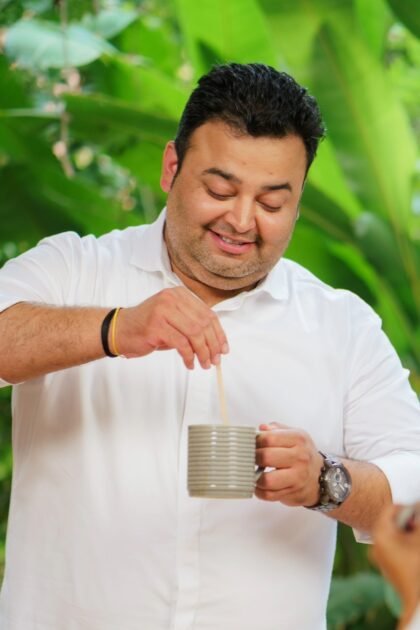 Man smiling while stirring tea in white shirt