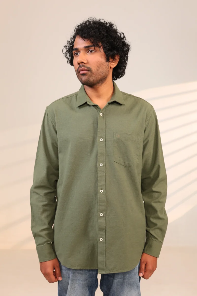 Man in olive green shirt standing confidently.