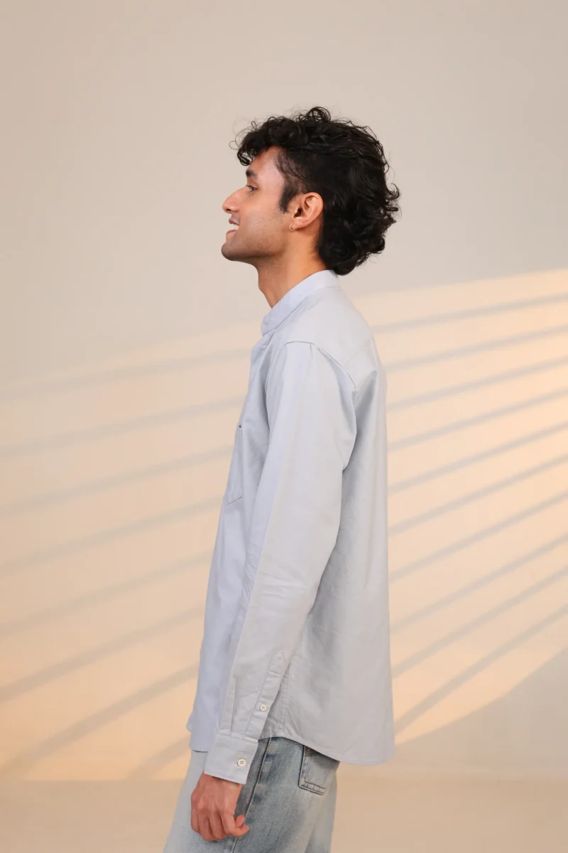 Side profile of man in light blue shirt with shadows.