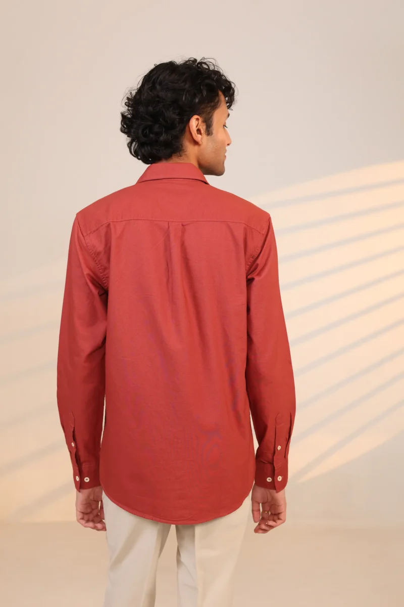 Rear view of rust-red shirt with long sleeves.