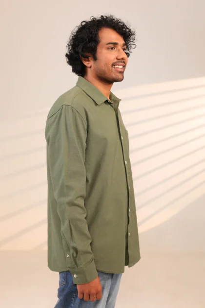 Man in olive green shirt side profile while smiling.