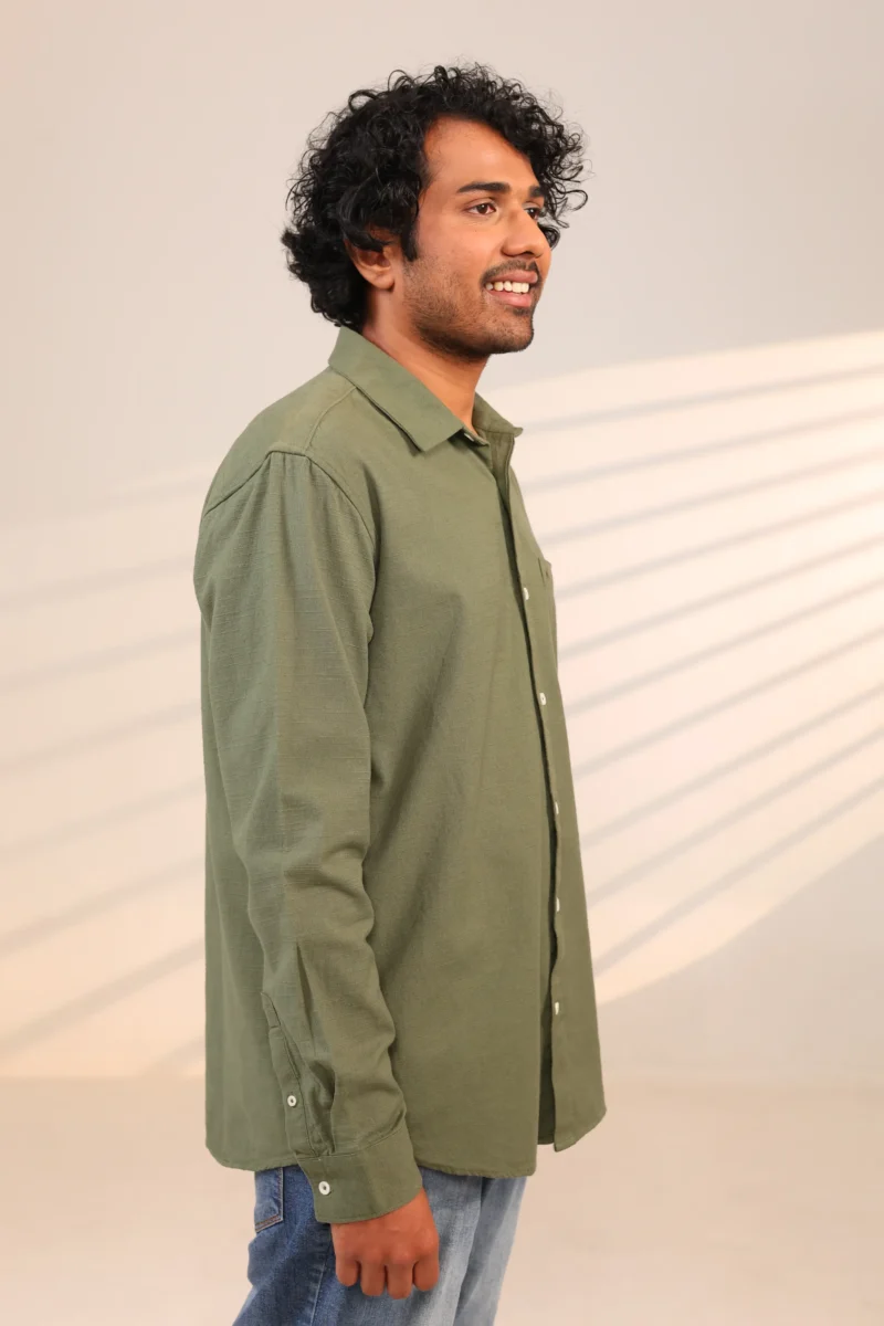 Man in olive green shirt side profile while smiling.