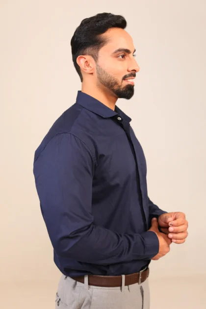 Man in navy shirt facing left with confident stance.
