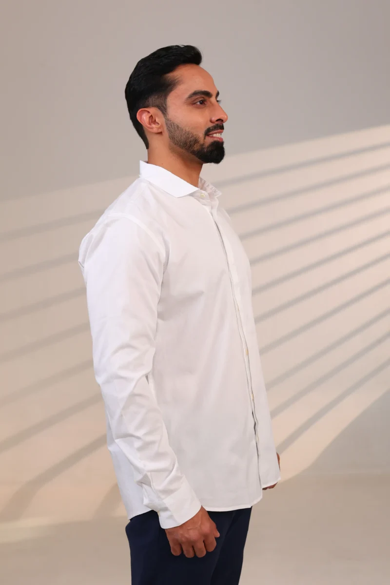 Man in white shirt facing front, smiling faintly.