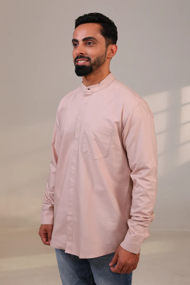 Man wearing a beige mandarin collar shirt standing sideways.